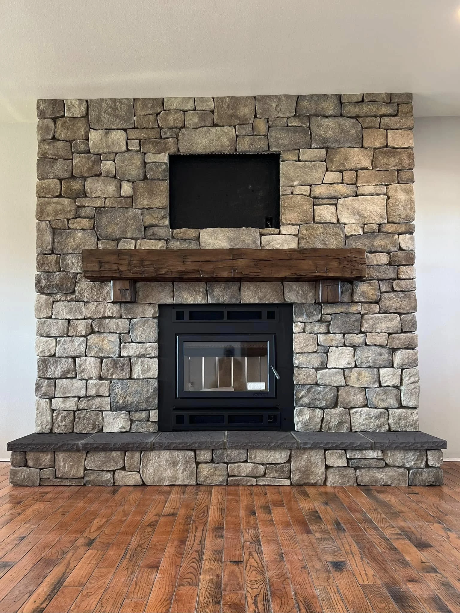 Rustic stone fireplace and hearth built by Alano Masonry