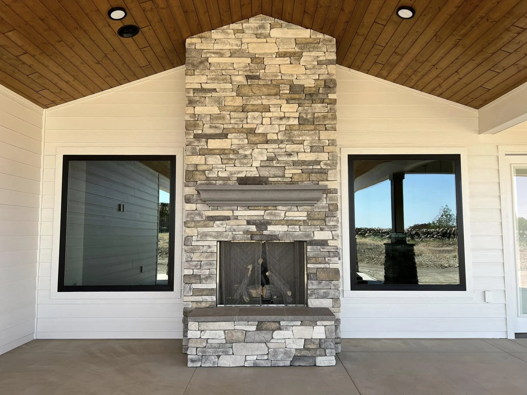 Covered outdoor stone fireplace with a substantial hearth and timber ceiling